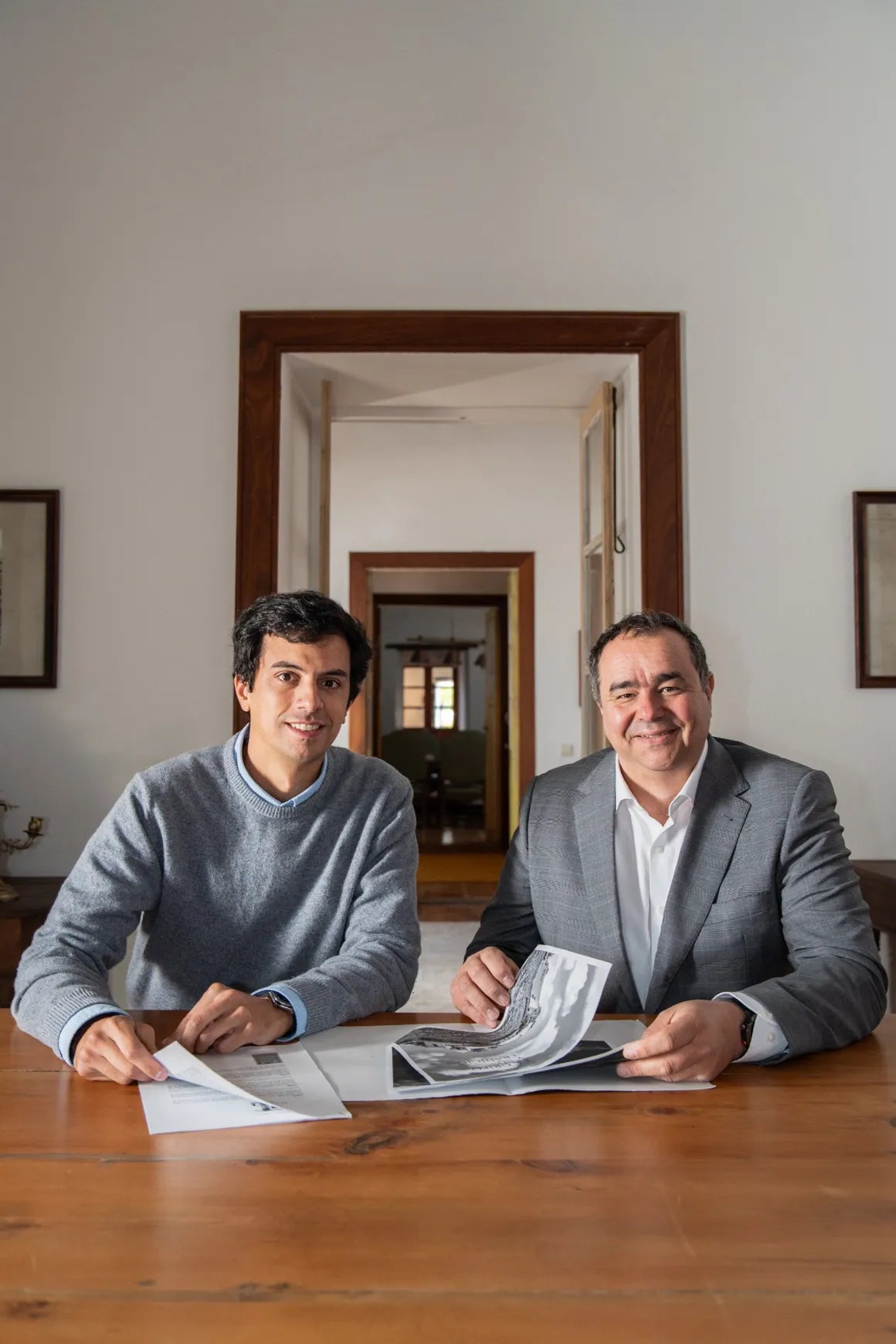 Miembros del equipo directivo sentados a una mesa de madera, revisando documentos en un ambiente elegante y tradicional.